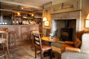 un bar con chimenea, mesa y sillas en Ye Olde Cheshire Cheese en Longnor