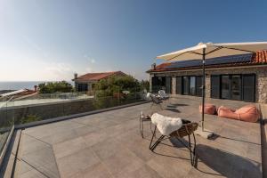 a patio with an umbrella and chairs and a house at Vila Coratina ZadarVillas in Lun