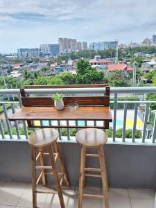 una mesa de madera y 2 taburetes en el balcón en Stylish 1BR with Wifi and Queen size bed in Grace Res en Manila