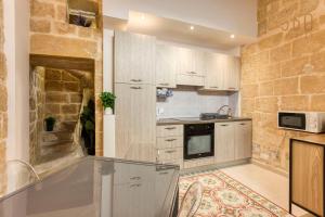 uma cozinha com uma parede de pedra e um balcão em Authentic 2BR House of Character with Terrace by 360 Estates em Naxxar
