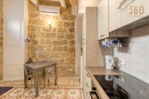 uma cozinha com uma mesa e uma parede de pedra em Authentic 2BR House of Character with Terrace by 360 Estates em Naxxar