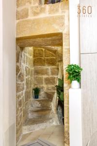 uma parede de pedra com escadas num quarto com plantas em Authentic 2BR House of Character with Terrace by 360 Estates em Naxxar