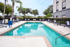 una piscina en un hotel con sillas y un edificio en Hampton Inn & Suites Tampa-East/Casino/Fairgrounds, en Seffner