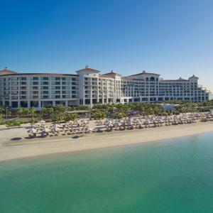 a hotel on the beach with chairs and umbrellas at Waldorf Astoria Dubai Palm Jumeirah in Dubai