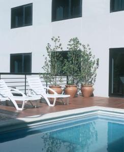 une paire de chaises blanches assises à côté d'une piscine dans l'établissement NH Mendoza Cordillera, à Mendoza