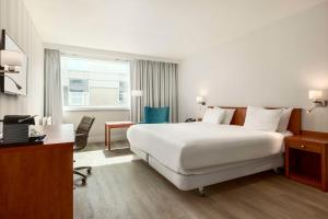 a hotel room with a large white bed and a desk at NH Amsterdam Schiphol Airport in Hoofddorp