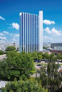 un gran edificio blanco con árboles delante de él en Congress Hotel Chemnitz en Chemnitz