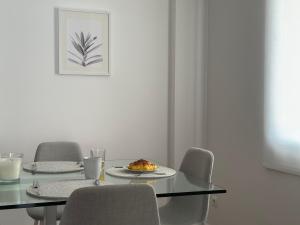 uma sala de jantar com uma mesa com cadeiras e um prato de comida em Tropical Garden no Caniço