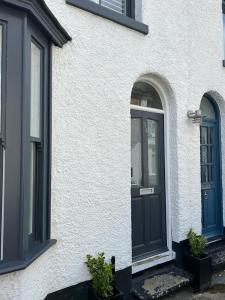 a white house with a black door and two windows at Divers Cottage - Central Whitstable in Whitstable