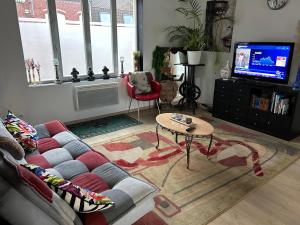 a living room with a couch and a table and a tv at Haylenes in Tourcoing