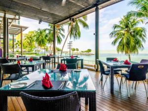 un restaurante con mesas y sillas y vistas al océano en Mercure Penang Beach, en George Town