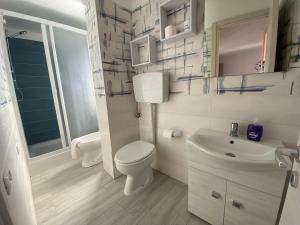 a white bathroom with a toilet and a sink at Nora's Flats in Triscina