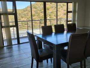 a dining room table with chairs and a large window at Hopslot Villa in Mossel Bay