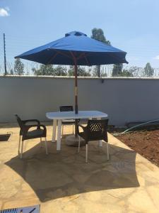 a blue umbrella sitting on a table with two chairs at Emily Apartments Kisumu on Hatupe Enterprises Ltd Building in Kibos