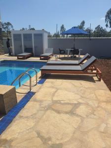 a swimming pool with chairs and an umbrella at Emily Apartments Kisumu on Hatupe Enterprises Ltd Building in Kibos