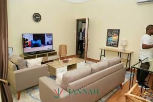 Ein Mann steht in einem Wohnzimmer mit einer Couch und einem Fernseher. in der Unterkunft JANNAH VILLAH in Accra