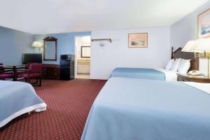 Großes Hotelzimmer mit 2 Betten und einem Tisch in der Unterkunft Travelodge by Wyndham Las Vegas NM in Las Vegas