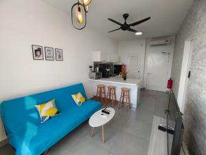 a living room with a blue couch and a kitchen at Kanvas Soho Cyberjaya/Netflix/Gym/Jacuzzi/KLIA in Cyberjaya