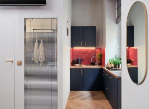 a kitchen with blue cabinets and red tiles at Hidden Garden Apartments in Łódź