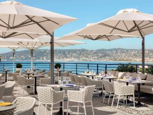 ジュアン・レ・パンにあるLe 1932 Hotel & Spa Cap d'Antibes - MGalleryのテーブル、椅子、パラソルが備わるレストラン
