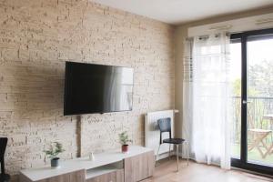 uma sala de estar com televisão numa parede de tijolos em Large cosy nest with balcony in Aubervilliers em Aubervilliers