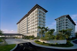 a large white building with palm trees in front of it at The Mermoon Resort Hainan Tufu Bay, Tapestry By Hilton in Lingshui