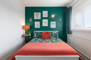 - une chambre avec un lit rouge et un mur vert dans l'établissement Harleys Way - Short Walk to Beach and Village, à Saundersfoot