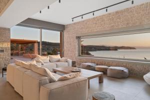 a living room with couches and a large window at Villa Olea - Luxury Villa with Swimming pool, Tennis court & Beach Volley in Koilás