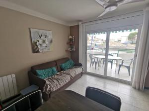 uma sala de estar com um sofá, uma mesa e uma varanda em Appartement avec Piscine et Vue Canaux em Roses