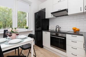 a kitchen with white cabinets and a white table with a dining room at Beautiful & Comfortable Spacious Apartment in Gdansk by Renters in Gdańsk