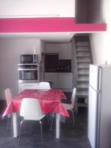 a kitchen with a table and chairs with a red table cloth at Marendes Des Palombes 2 in Le Barcarès