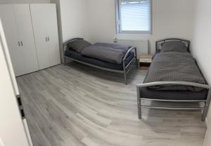 two beds in a room with wooden floors at AlWi Appartements Moringen in Moringen