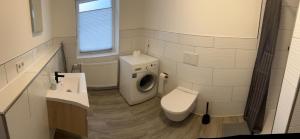 y baño con lavadora y aseo. en AlWi Appartements, en Moringen