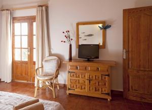 een slaapkamer met een tv op een dressoir met een spiegel bij Ca Na Rita den Constantino - Formentera Break in Playa Migjorn