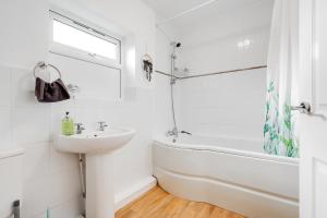 a white bathroom with a sink and a bath tub and a window at Chique Manchester Abode - Parking - 8mins to City in Manchester