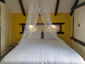um quarto com uma cama branca e uma rede mosquiteira em Achadinha - Mountain Cottage em Arco da Calheta