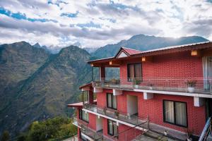 a red building with mountains in the background at Aaryam Resort, Auli in Joshīmath