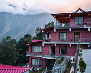 a red building with a mountain in the background at Aaryam Resort, Auli in Joshīmath