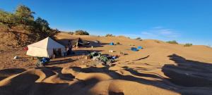 a group of tents in the sand in a desert at Mhamid wild Trekking Camels in Mhamid