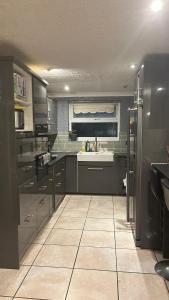 cocina con electrodomésticos de acero inoxidable y suelo de baldosa en Home Away in a Close en Thamesmead