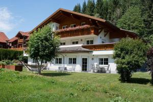 a large white house with chairs in a yard at Ferienwohnung Carbonare in Sankt Gallenkirch