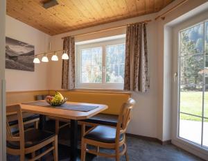 a dining room with a table and chairs and windows at Ferienwohnung Carbonare in Sankt Gallenkirch
