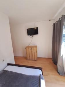 1 dormitorio con 1 cama y TV en la pared en Apartments HN, en Igalo