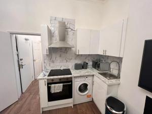 a kitchen with a stove and a washing machine at Iconic One Bed Apartment in Chiswick in London