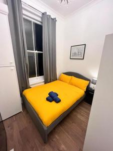 a bedroom with a yellow bed with a blue bow on it at Iconic One Bed Apartment in Chiswick in London