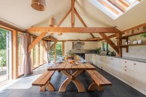 uma cozinha com uma mesa de madeira e algumas janelas em Otter's Cottage em Holbeton