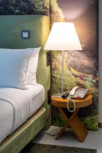 a lamp on a table next to a bed with a phone at DoubleTree by Hilton Lisbon Fontana Park in Lisbon