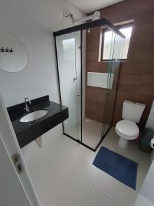 a bathroom with a shower and a toilet and a sink at Residencial Brisa do Mar in Bombinhas