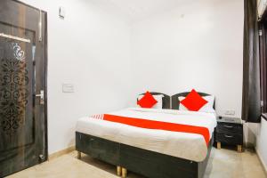 1 dormitorio con 1 cama grande con almohadas rojas en OYO Welcome Residency, en Gurgaon