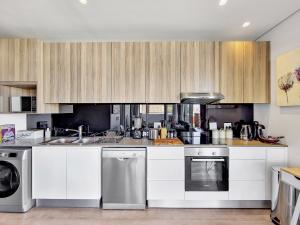 uma cozinha com armários brancos e electrodomésticos de aço inoxidável em Sentinel the Heart of the Cape na Cidade do Cabo